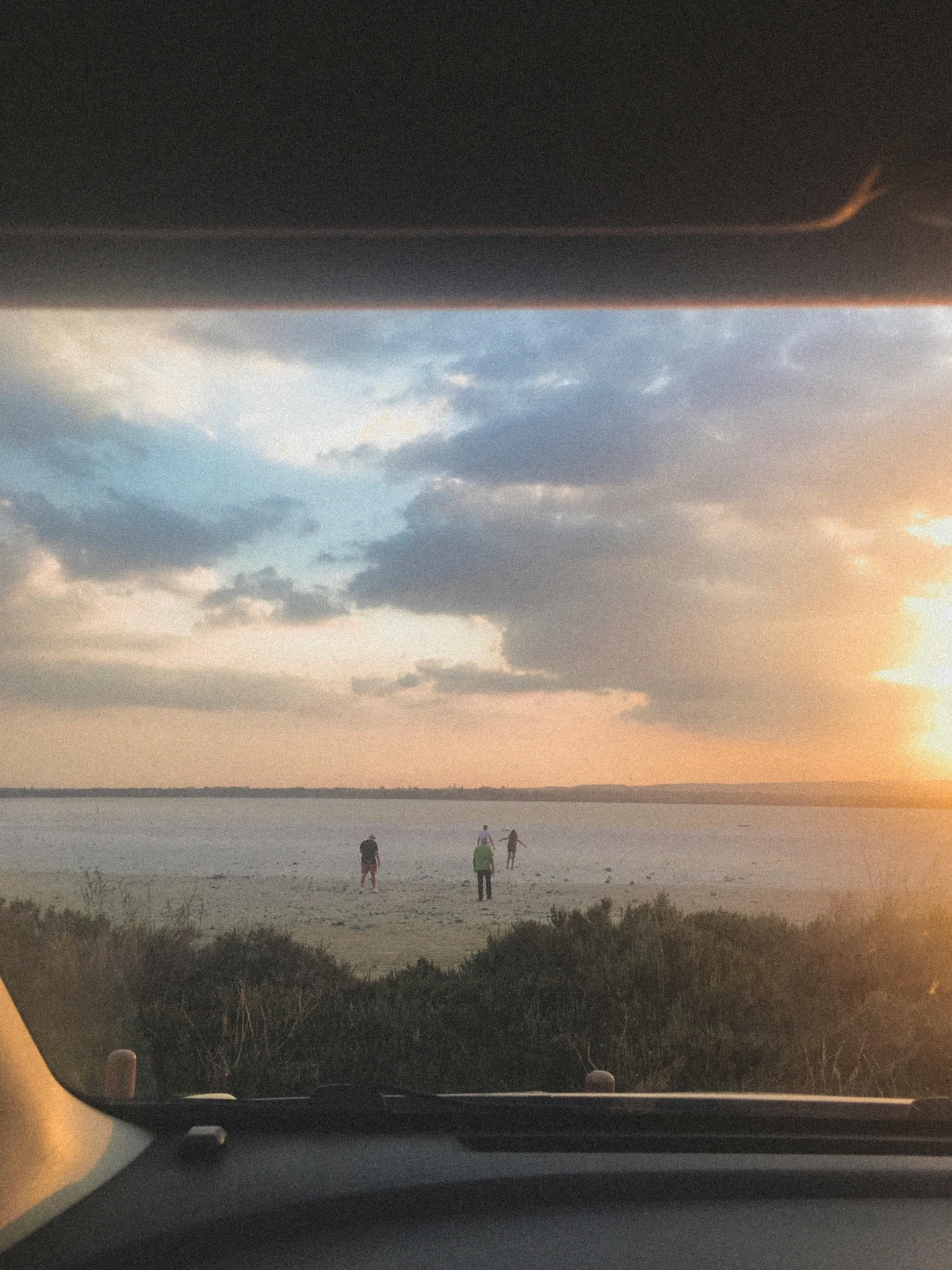 Warm analog photo looking through a car window toward a lake at sunset